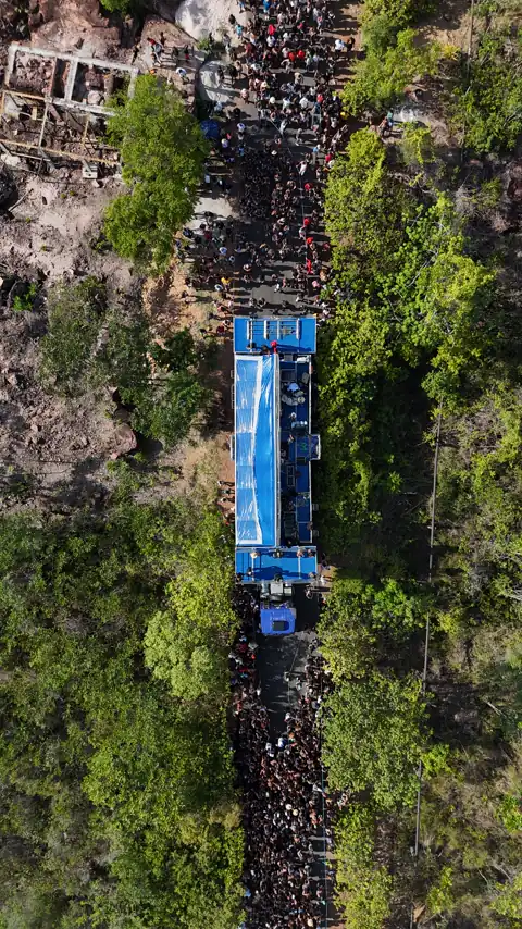 Vista aérea do trio azul na estrada, com a multidão dos dois lados