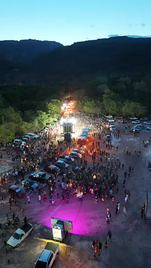 Vista aérea da praça à noite, com luzes e gente reunida